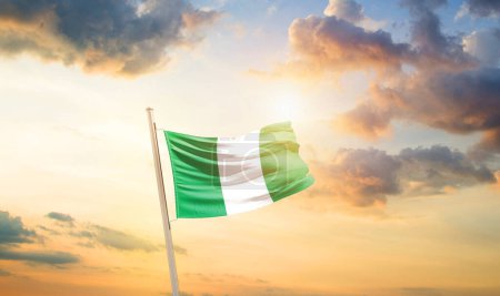 Photo for Nigeria waving flag in beautiful sky with clouds and sun - Royalty Free Image