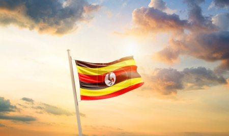 Photo for Uganda waving flag in beautiful sky with clouds and sun - Royalty Free Image