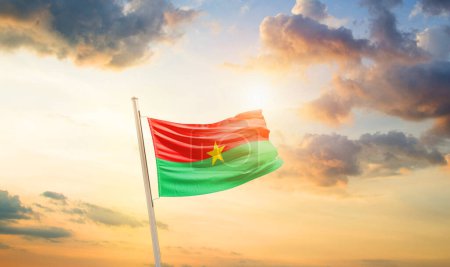 Photo for Burkina Faso waving flag in beautiful sky with clouds and sun - Royalty Free Image