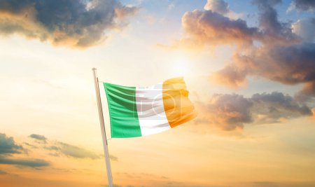 Foto de Irlanda ondeando bandera en el hermoso cielo con nubes y sol - Imagen libre de derechos