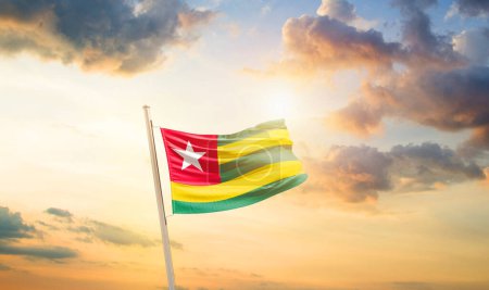 Téléchargez les photos : Togo agitant le drapeau dans un ciel magnifique avec des nuages et du soleil - en image libre de droit