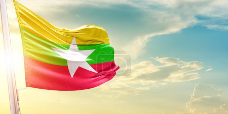 Foto de Bandera de Myanmar contra el cielo con nubes y sol - Imagen libre de derechos