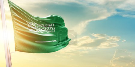 Foto de Bandera de Arabia Saudita contra el cielo con nubes y sol - Imagen libre de derechos