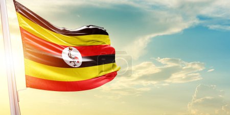 Photo for Uganda flag against sky with clouds and sun - Royalty Free Image