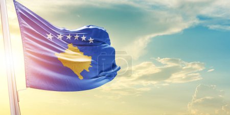 Téléchargez les photos : Drapeau du Kosovo contre le ciel avec nuages et soleil - en image libre de droit