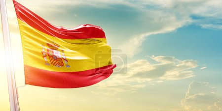 Foto de Bandera de España contra el cielo con nubes y sol - Imagen libre de derechos