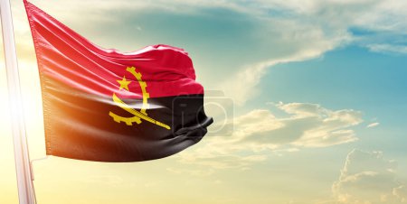 Téléchargez les photos : Drapeau Angola contre ciel avec nuages et soleil - en image libre de droit