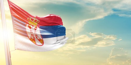 Téléchargez les photos : Drapeau de Serbie contre ciel avec nuages et soleil - en image libre de droit