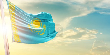 Foto de Bandera de Kazajistán contra el cielo con nubes y sol - Imagen libre de derechos