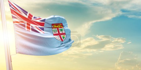Foto de Bandera de Fiyi contra el cielo con nubes y sol - Imagen libre de derechos