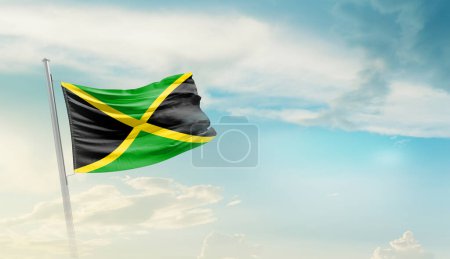 Jamaica waving flag against blue sky with clouds