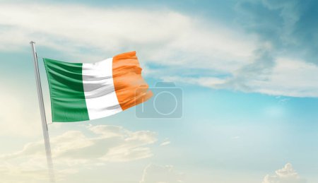Irlanda ondeando bandera contra las nubes y el cielo