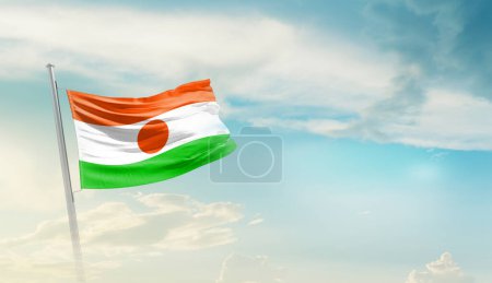 Téléchargez les photos : Niger agitant le drapeau contre le ciel bleu avec des nuages - en image libre de droit