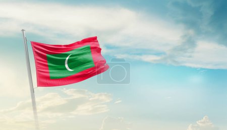 Maldivas ondeando bandera contra el cielo azul con nubes