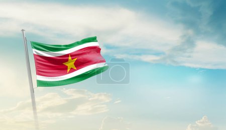 Suriname waving flag against blue sky with clouds