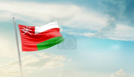 Oman waving flag against blue sky with clouds