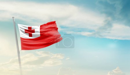 Tonga schwenkt Flagge gegen blauen Himmel mit Wolken
