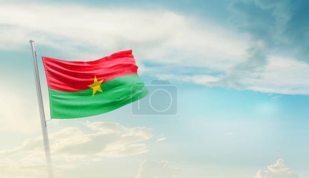 Burkina Faso ondeando bandera contra el cielo azul con nubes