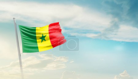 Senegal schwenkt Flagge gegen blauen Himmel mit Wolken
