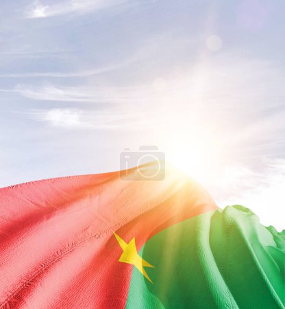 Téléchargez les photos : Burkina Faso agitant le drapeau contre le ciel bleu avec des nuages - en image libre de droit