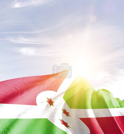 Burundi schwenkt Flagge gegen blauen Himmel mit Wolken 