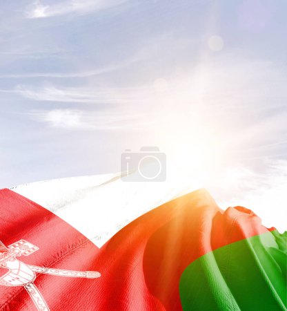Omán ondeando bandera contra el cielo azul con nubes