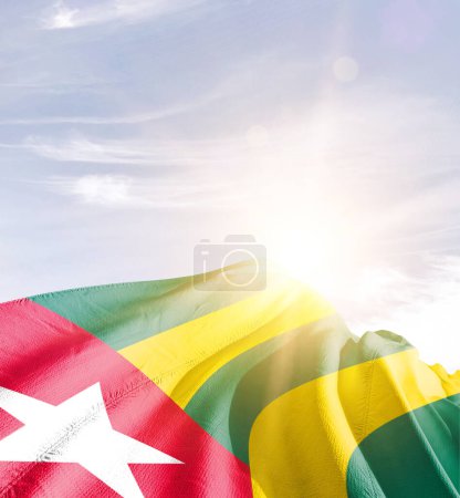 Téléchargez les photos : Togo agitant drapeau contre ciel bleu avec des nuages - en image libre de droit