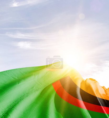 Téléchargez les photos : Zambie agitant le drapeau contre le ciel bleu avec des nuages - en image libre de droit