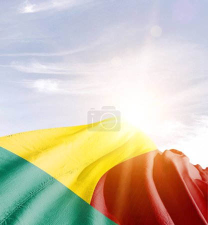 Benin schwenkt Flagge gegen blauen Himmel mit Wolken