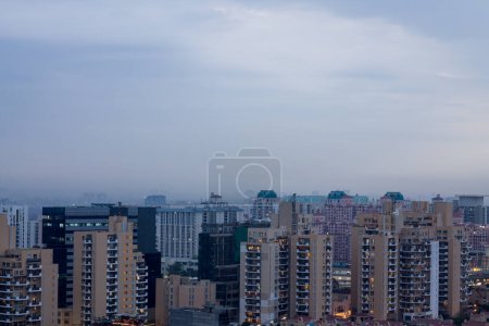 Gurgaon, Haryana, Inde coucher de soleil coloré sur une soirée d'hiver brumeux.Vue aérienne du paysage urbain de Gurugram avec une architecture moderne, commercial, immeubles d'appartements résidentiels de luxe.Delhi NCR belle skyline avec des lumières de la ville.