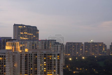 Téléchargez les photos : Gurgaon, Haryana, Inde coucher de soleil coloré sur une soirée d'hiver brumeux.Vue aérienne du paysage urbain de Gurugram avec une architecture moderne, commercial, immeubles d'appartements résidentiels de luxe.Delhi NCR belle skyline avec des lumières de la ville. - en image libre de droit