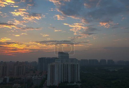 Téléchargez les photos : Gurgaon, Haryana, Inde skyline avec coucher de soleil coloré pendant les moussons.Vue aérienne du paysage urbain de Gurugram avec architecture moderne, commercial, immeubles d'appartements résidentiels de luxe.Lumières de la ville le soir dans le quartier des affaires premium, Delhi RCN. - en image libre de droit