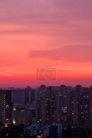 Téléchargez les photos : Gurgaon, Haryana, Inde skyline avec coucher de soleil coloré pendant les moussons.Vue aérienne du paysage urbain de Gurugram avec architecture moderne, commercial, immeubles d'appartements résidentiels de luxe.Lumières de la ville le soir dans le quartier des affaires premium, Delhi RCN. - en image libre de droit
