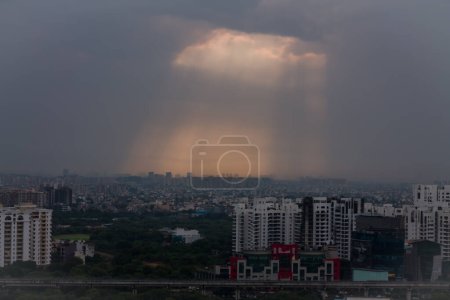 Gurgaon, Haryana, Indien Stadtsilhouette bei Sonnenuntergang. Gurugram Stadtbild mit moderner Architektur, kommerziellen und luxuriösen Wohngebäuden. Sonnenstrahlen nach unten, Wolkendecke während des Monsun.Geschäftsviertel in Delhi NCR.