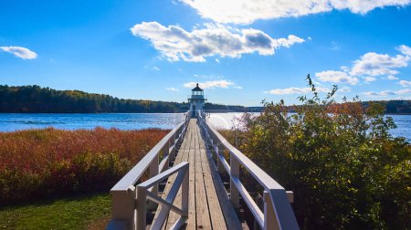 Photo for Image of Small boardwalk pedestrian walkway bridge with gate leading towards tiny Maine lighthouse - Royalty Free Image