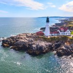 Image of Stunning lighthouse on rocky cliffs in Maine from aerial view