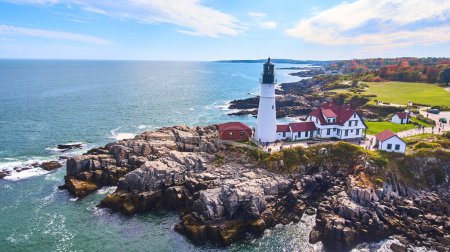 Téléchargez les photos : Image de la vue aérienne du littoral du Maine avec des falaises rocheuses et un phare blanc emblématique - en image libre de droit