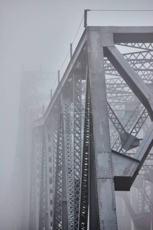 Foto de Imagen de Vertical mirando por un gran puente de acero que se desvanece en la mañana de niebla - Imagen libre de derechos