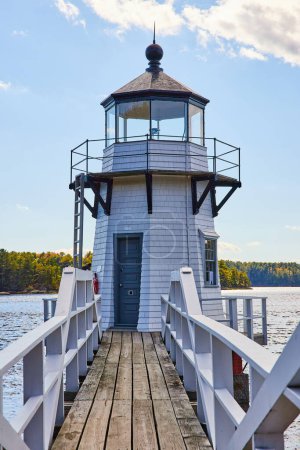 Photo for Image of Boardwalk with railing leads to small white lighthouse on Maine river - Royalty Free Image