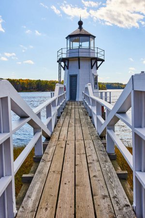 Photo for Image of Wood boardwalk with white railing leading to small Maine lighthouse - Royalty Free Image