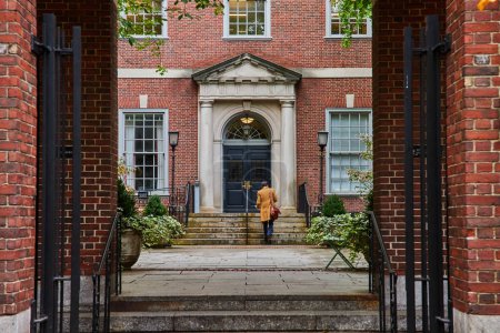 Bild eines Jurastudenten, der von Backsteinbögen in New York City geradeaus durch den Innenhof geht