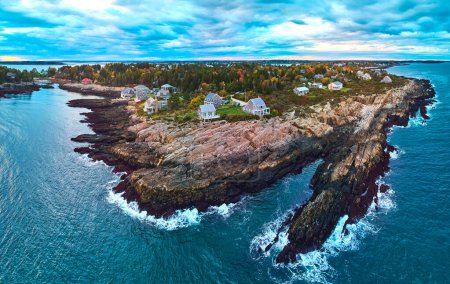 Téléchargez les photos : Image de Superbe antenne au-dessus des côtes rocheuses du Maine sur l'océan avec maisons, feuillage d'automne et lumière du crépuscule - en image libre de droit