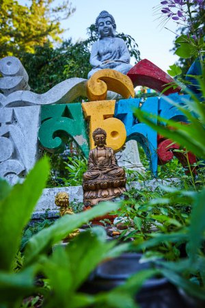Photo for Image of View of small buddha statues through garden plants - Royalty Free Image