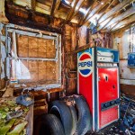 Image of Destroyed interior of abandoned space with Pepsi vending machine, tires, and rotary phone