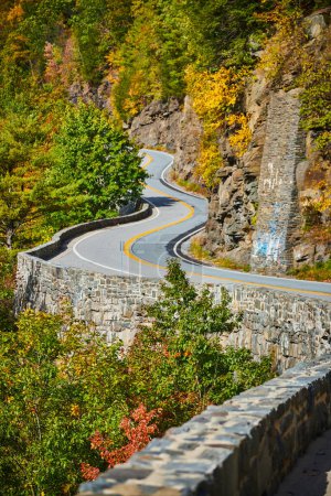 Foto de Imagen de Hermoso camino sinuoso con muro de piedra a lo largo del borde del acantilado en las montañas - Imagen libre de derechos