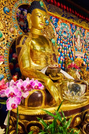 Téléchargez les photos : Image d'une statue de Bouddha en or décoré dans un sanctuaire avec des orchidées roses - en image libre de droit