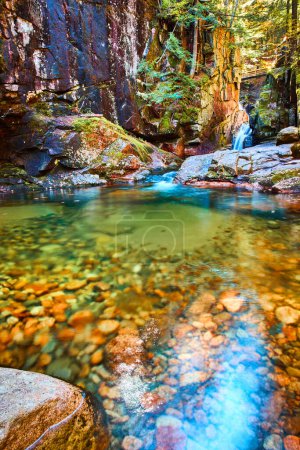 Téléchargez les photos : Image de l'eau claire de la rivière avec de petites roches et un canyon avec une cascade en arrière-plan - en image libre de droit