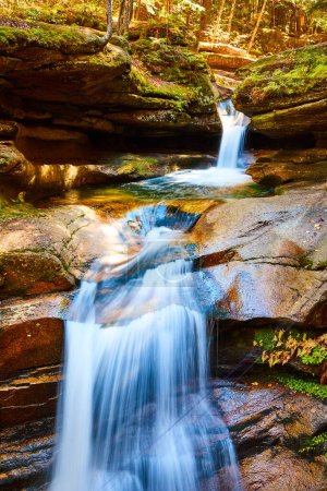 Téléchargez les photos : Image de cascades avec flou de mouvement à travers la forêt d'automne sereine avec des roches moussues et la forêt - en image libre de droit