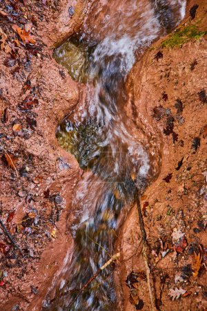 Téléchargez les photos : Image du ruisseau River en argile sculptant un motif ondulé avec des feuilles d'automne d'en haut - en image libre de droit