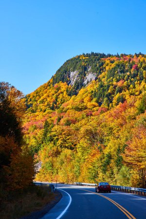 Téléchargez les photos : Image de Beau feuillage couvre montagne rocheuse vue de la route avec voiture passant par - en image libre de droit